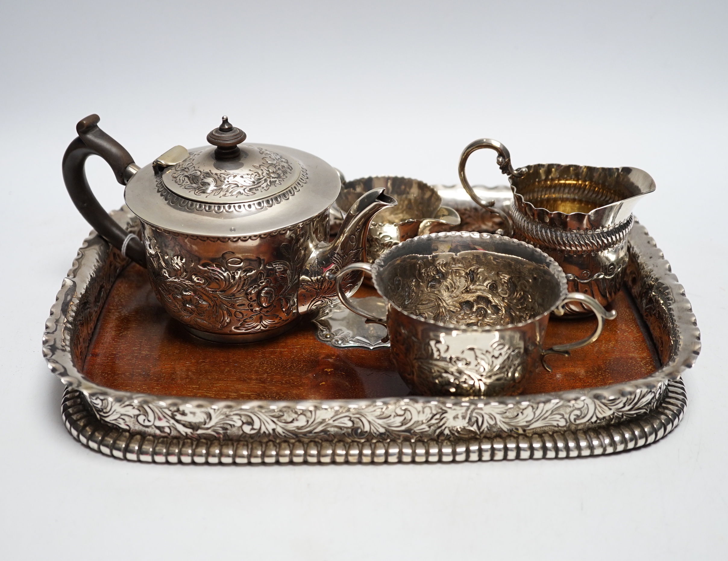 A matched Victorian repousse silver four piece bachelor's tea set, gross 12.8oz and silver plated? mounted wooden tea tray.
